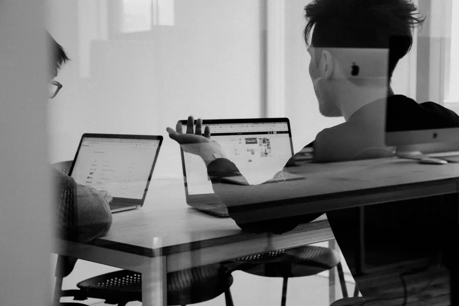 a person sitting at a desk with a laptop and a computer