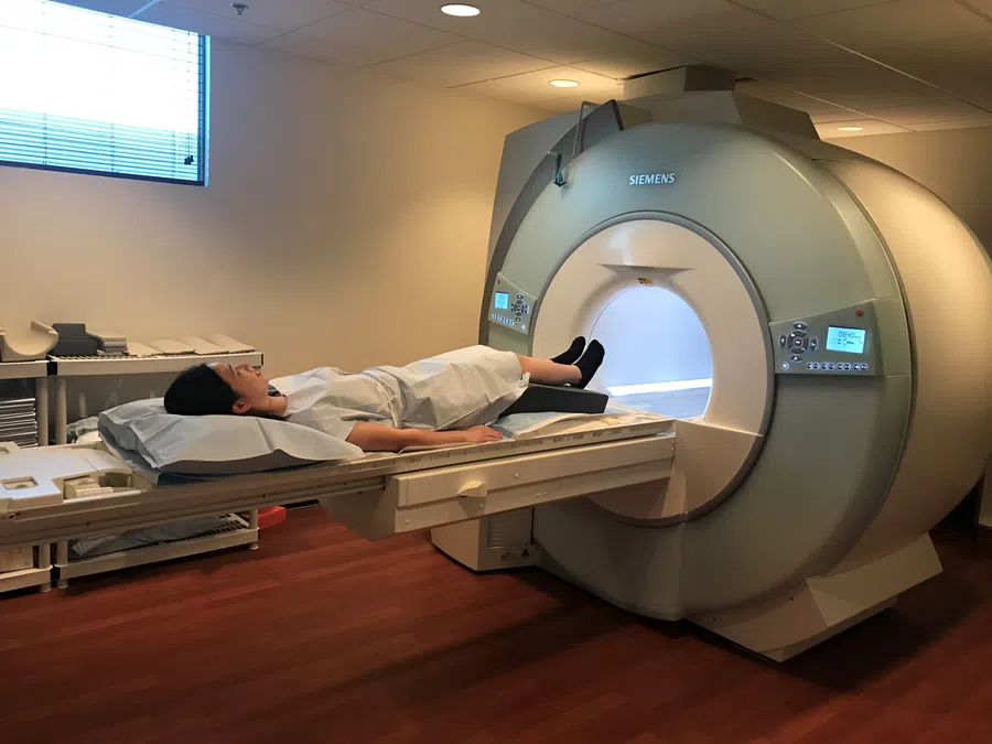Patient lying on MRI scanner bed ready for brain imaging in a modern medical facility room.