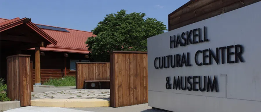 Entrance to Haskell Cultural Center and Museum with wooden structures and clear blue sky.