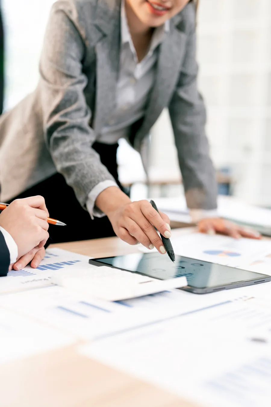 Business colleagues reviewing data on a tablet and discussing financial charts in an office setting