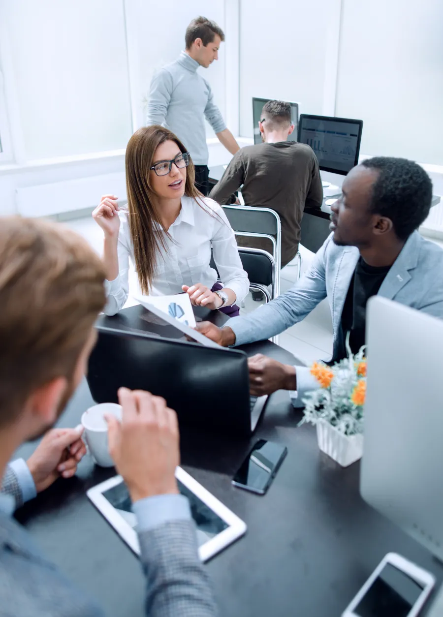a group of people sitting around a table with a laptop