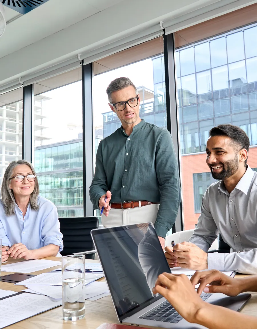 Business meeting with diverse professionals discussing ideas around a table in a bright office space.