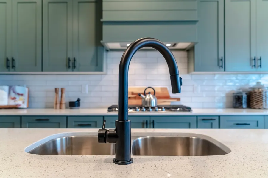 Plumber fixing a chrome sink pipe under a bathroom sink using plumbing tools and wrench.
