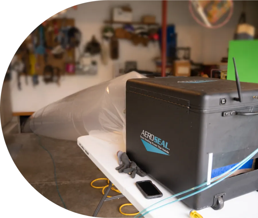 AeroSeal duct sealing equipment on a white table in a workshop with tools and gloves nearby