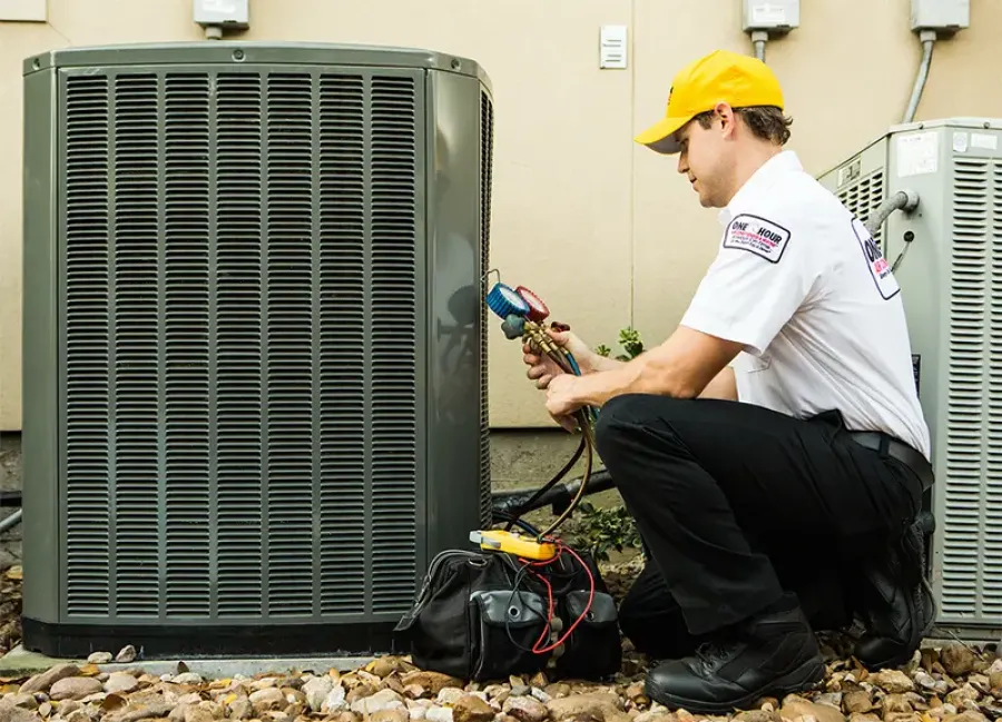 Technician in uniform checking and repairing an outdoor air conditioning unit with tools and gauges