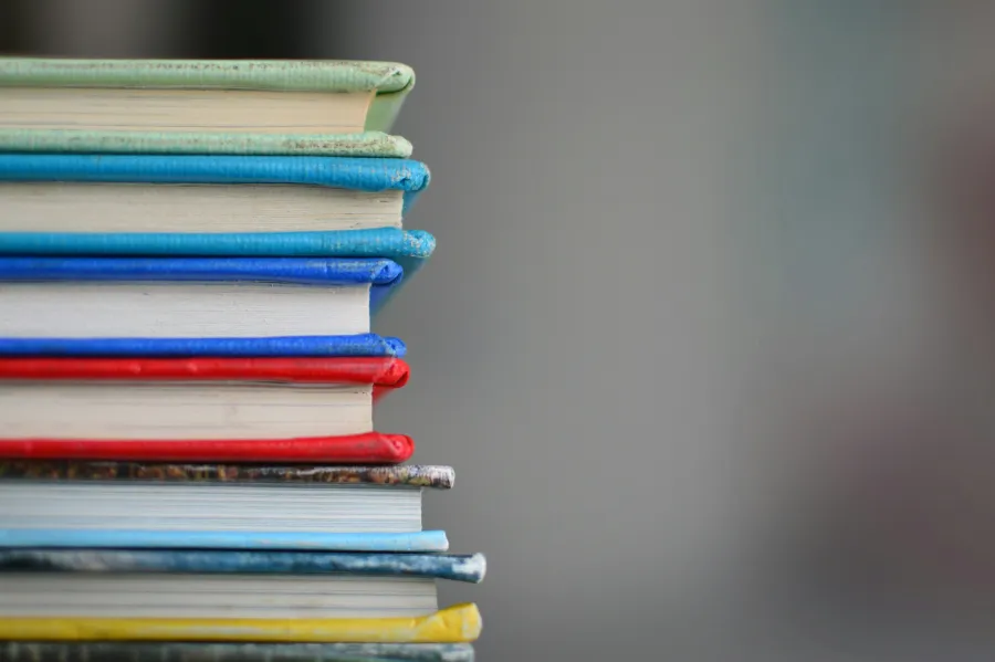Close-up of stacked colorful books with varying spine colors creating a vibrant visual effect.