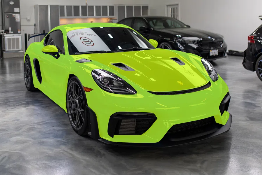 Bright green Porsche sports car in a showroom with black wheels and aggressive front design under indoor lighting