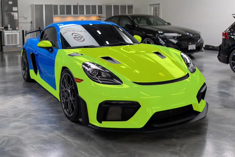 Bright green and blue sports car parked indoors with sleek design and black wheels