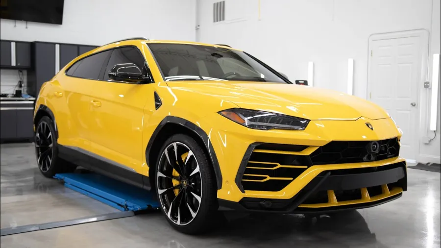 Yellow luxury Lamborghini SUV parked indoors with black accents and large rims.