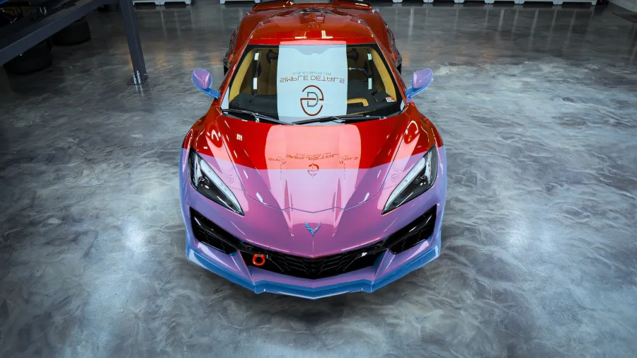 Front view of a red and purple custom sports car parked on a polished concrete floor indoors.