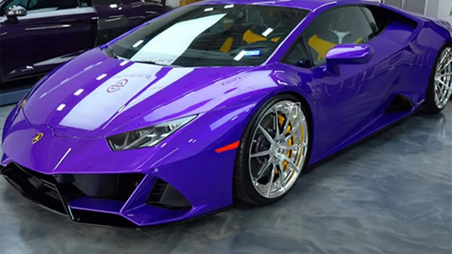 Sleek purple Lamborghini sports car with silver rims and yellow brake calipers in showroom