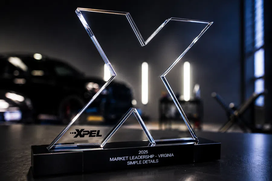 XPEL 2025 Market Leadership award in Virginia displayed on a clear acrylic X-shaped trophy on a black table.
