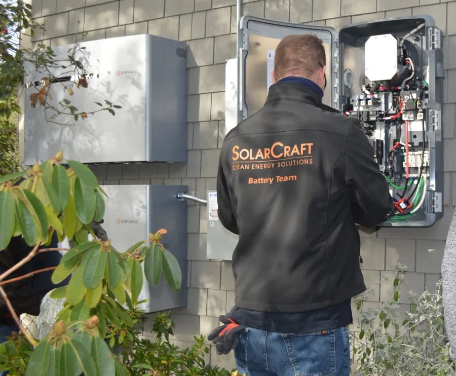 Technician from SolarCraft Battery Team working on solar energy equipment and battery system outdoors
