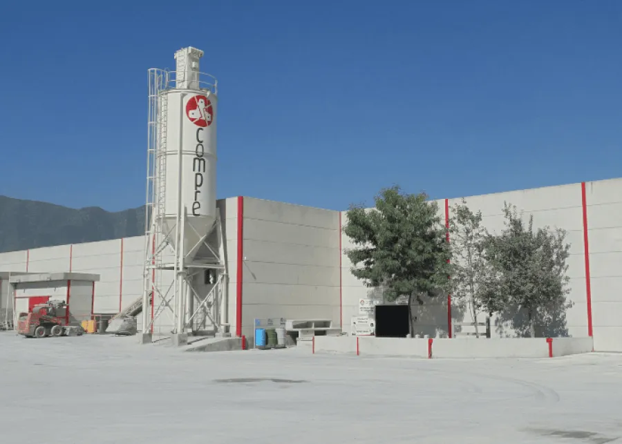 Industrial concrete plant with large silo, cement mixer truck, and warehouse under clear blue sky
