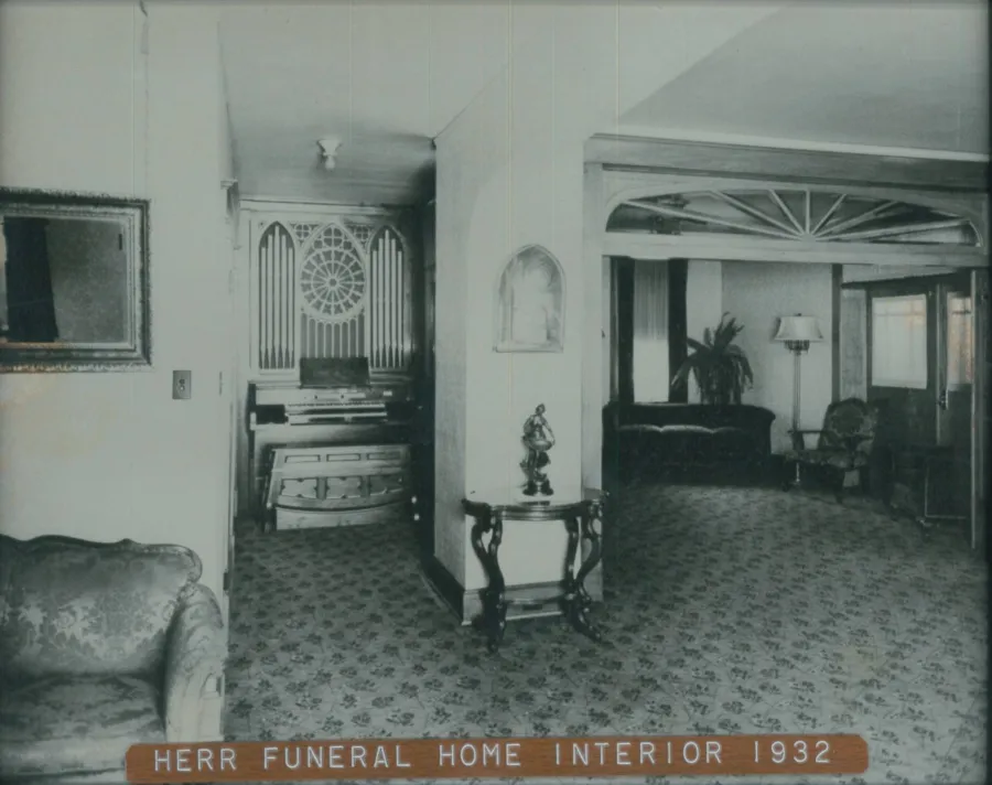 an old photo of a living room filled with furniture and a window