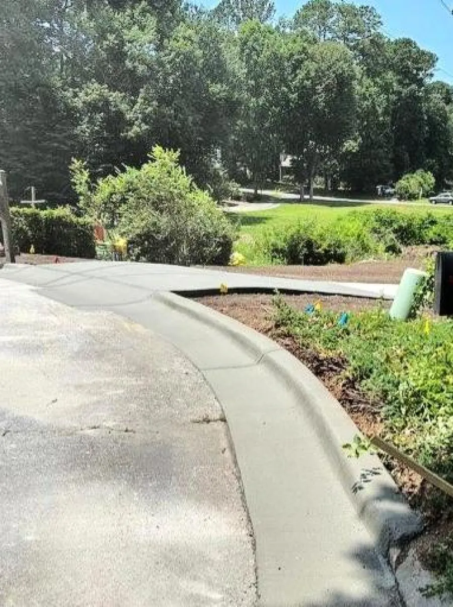 a sidewalk with trees and bushes