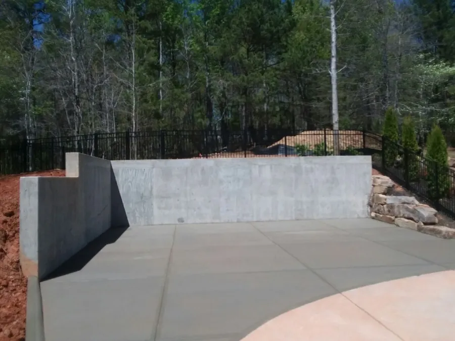 a concrete wall with a fence and trees in the background