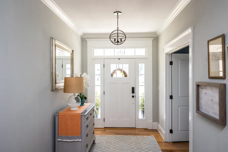 Bright and welcoming entryway with a modern light fixture and stylish decor elements.