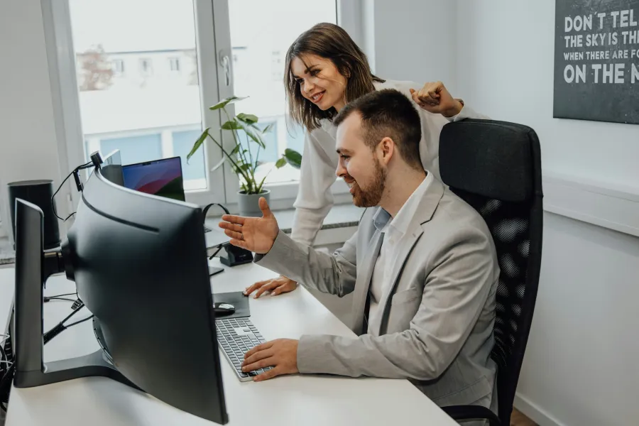 Man and woman collaborating on work at computer in a modern office with natural light and plants