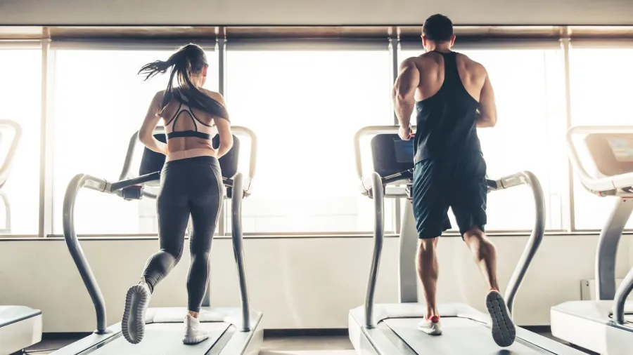 man and woman running on treadmills