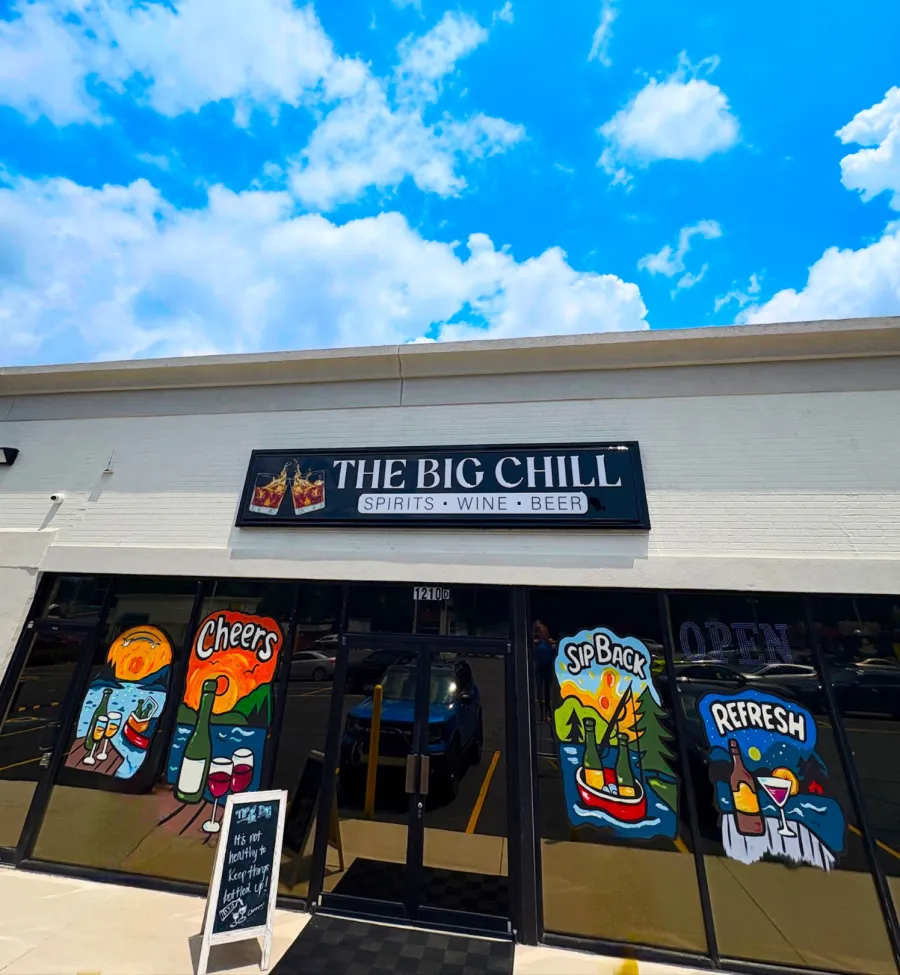 The Big Chill store front with colorful painted wine and beer glasses under a sunny blue sky with white clouds.