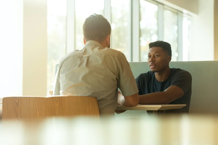 a man sitting at a desk looking at another man