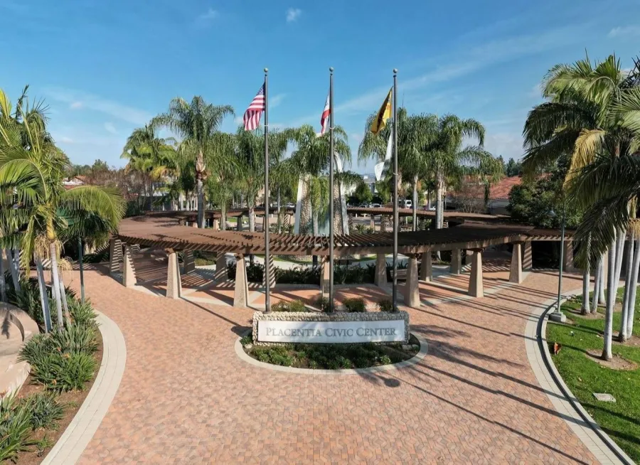 Placentia Civic Center entrance with flags, palm trees, and brick pathways on a clear sunny day