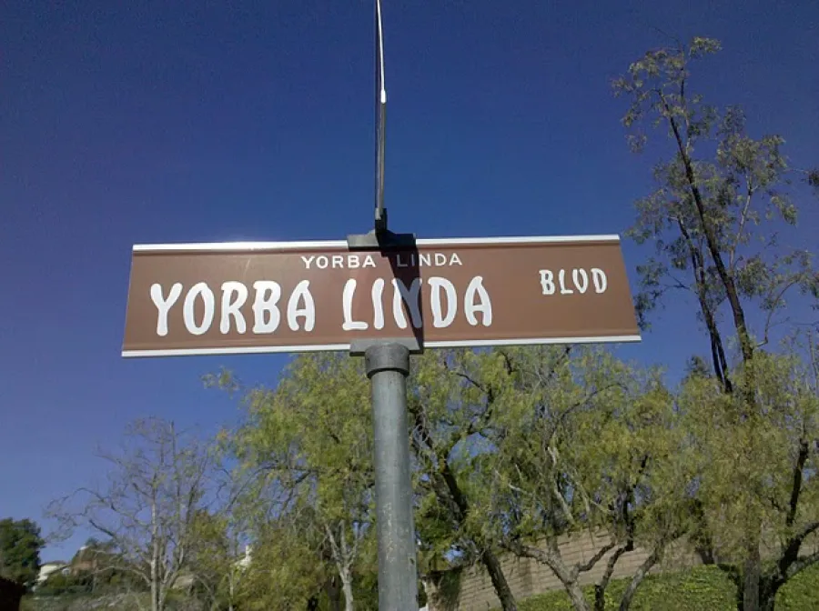 Brown Yorba Linda street sign on a pole with trees and clear blue sky in the background