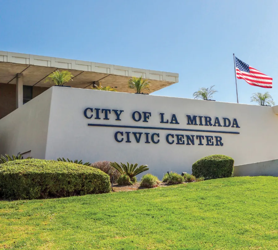 Modern civic center building in La Mirada with manicured lawn and American flag under clear blue sky