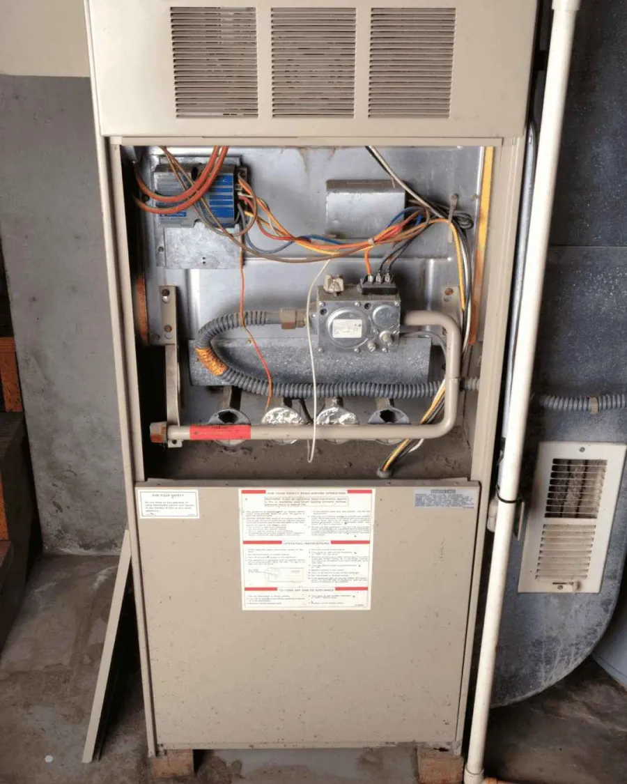 Technician using a torch to solder copper pipes on an air conditioning unit repair