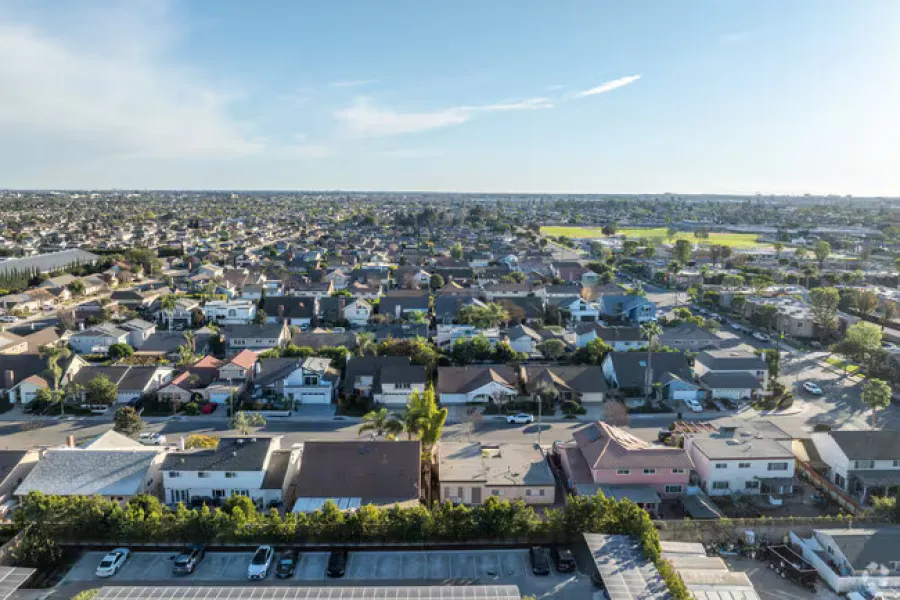 Aerial view of cypress, ca, a sprawling residential neighborhood with houses, streets, and greenery under a partly cloudy sky.