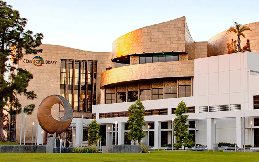 Cerritos Library building with modern curved architecture and outdoor sculpture at sunset.
