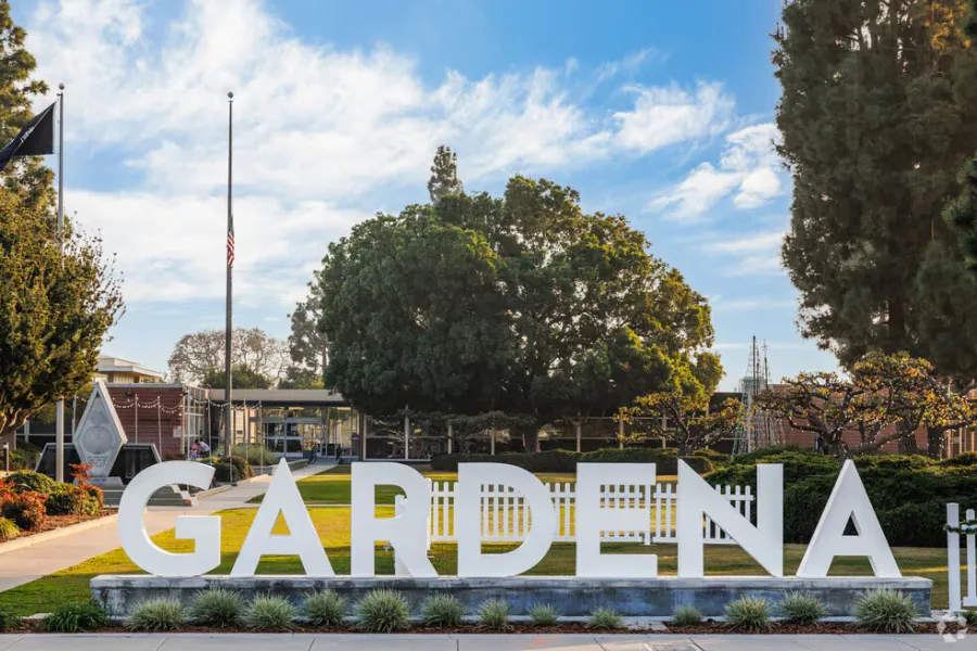 Large white Gardena sign on a grassy area with trees and blue sky in the background under daylight.