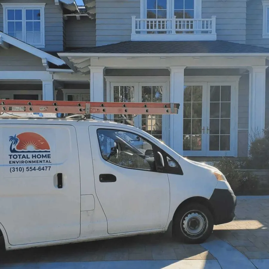 White service van with ladder on roof parked outside suburban home on sunny day