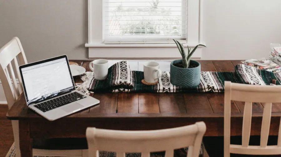 a table with a laptop and a shelf with books on it