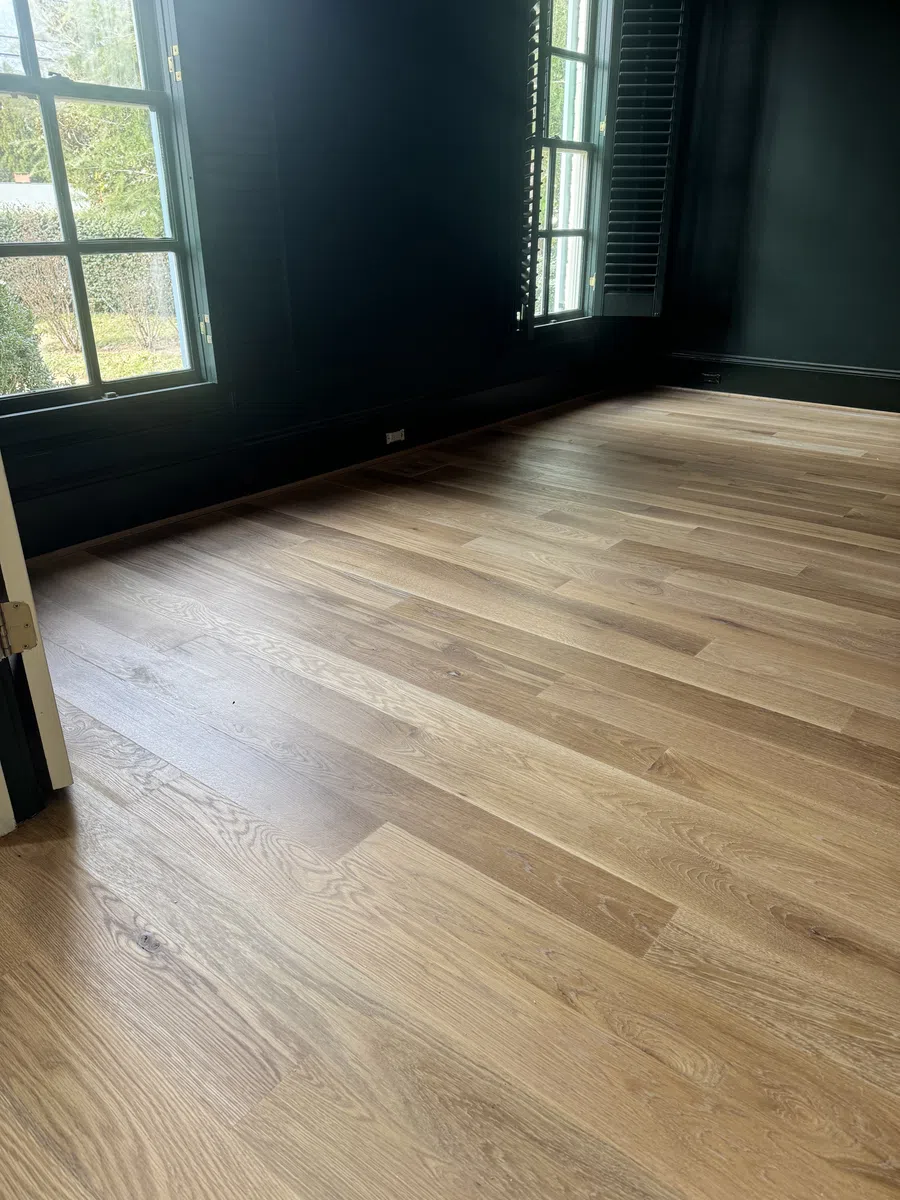 Spacious room with natural light, black walls, and newly installed light oak hardwood flooring.