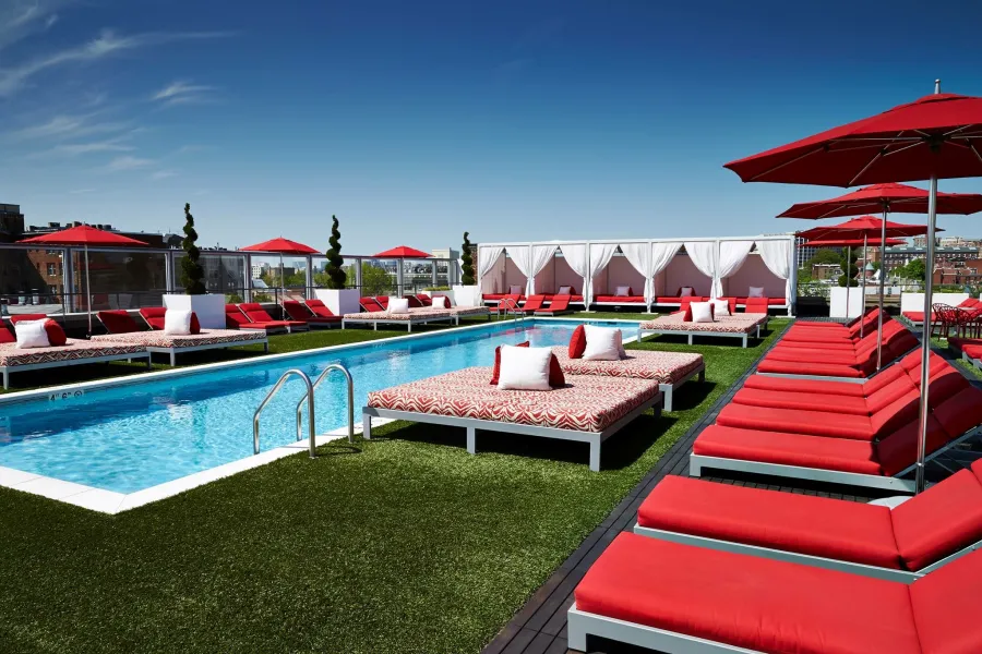 a pool with lounge chairs and umbrellas by it