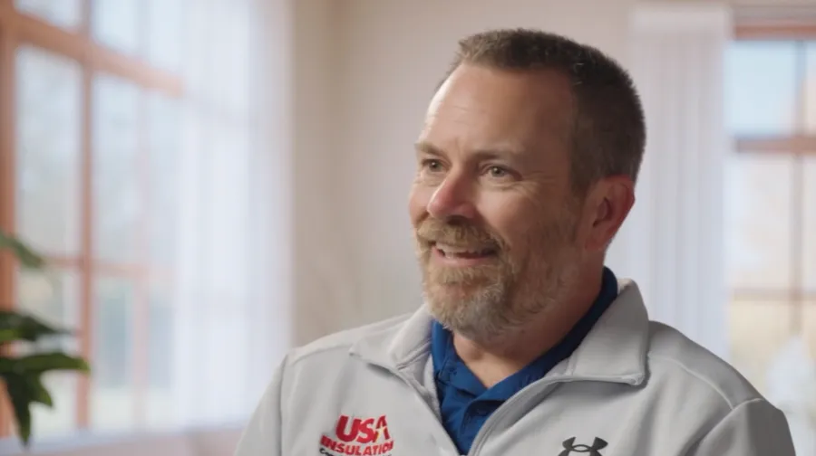 USA Insulation Owner Ryan Zondervan inside a bright room with large windows and white curtains.