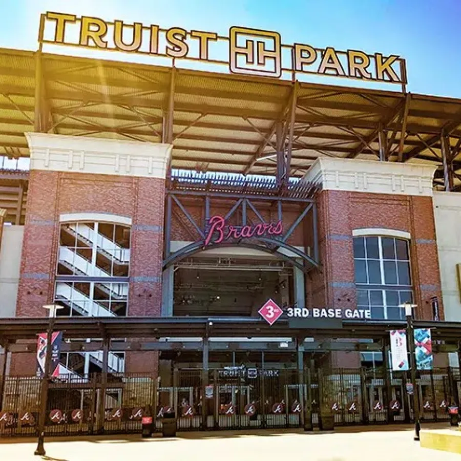 Front view of Truist Park entrance with Braves signage and statue under clear blue sky.