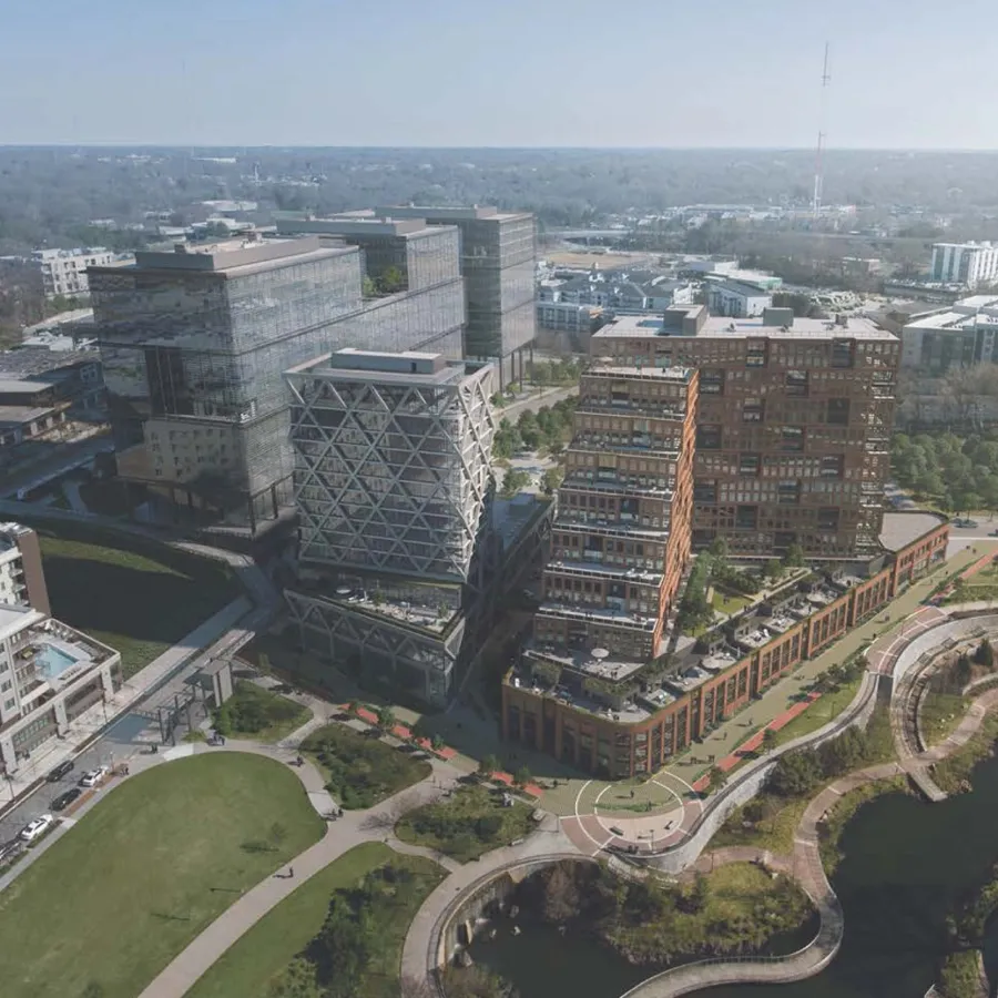 Aerial view of modern urban buildings with unique architecture alongside a curving riverside park and green spaces.