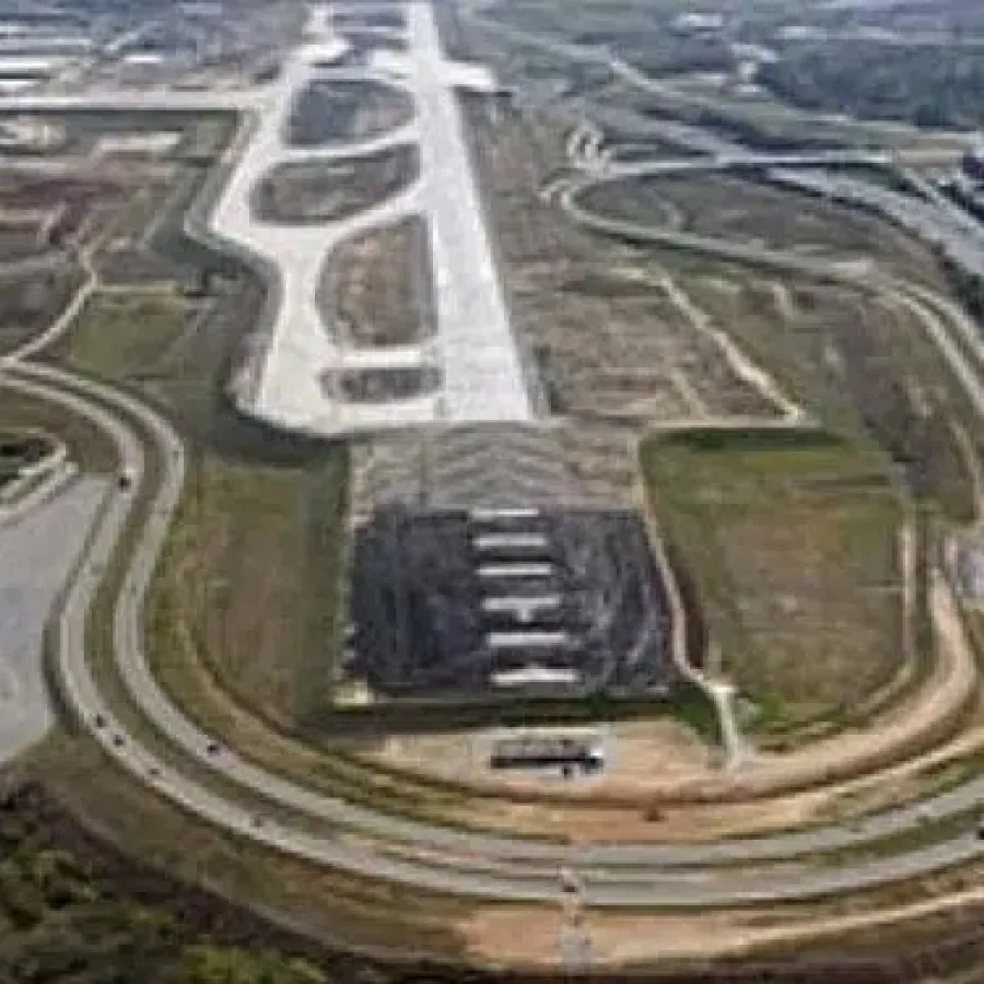Aerial view of a large industrial wastewater treatment facility surrounded by forest and multiple containment ponds.