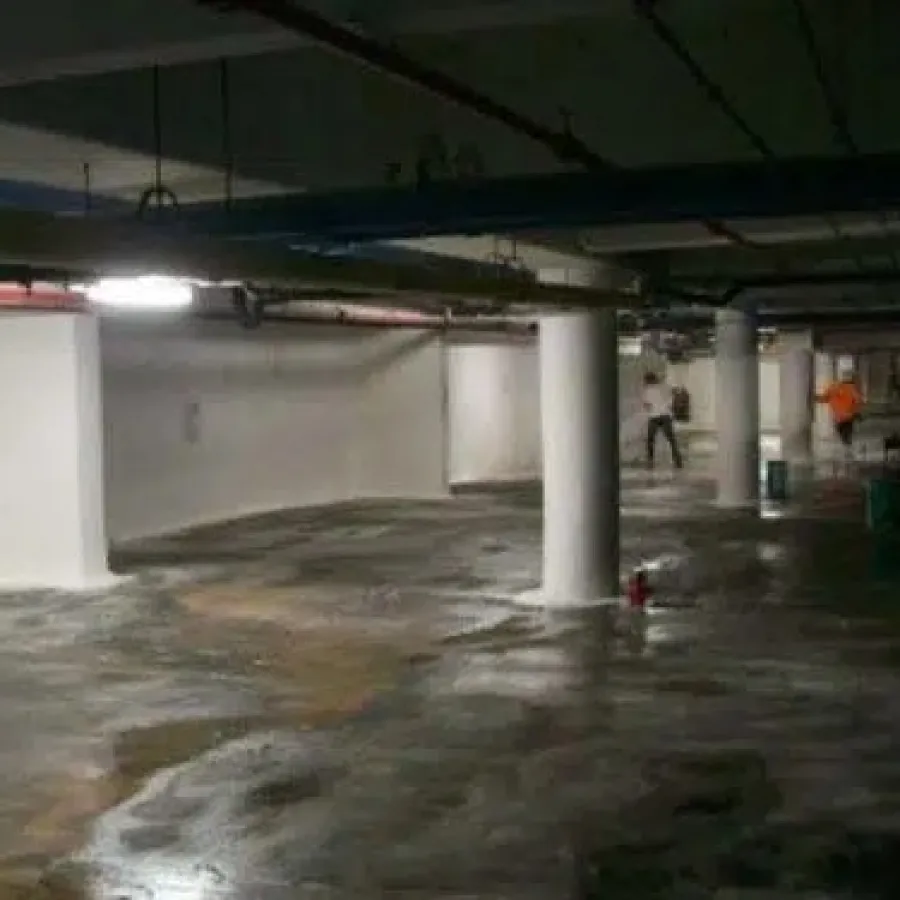 Dimly lit underground parking garage with wet concrete floor and white pillars