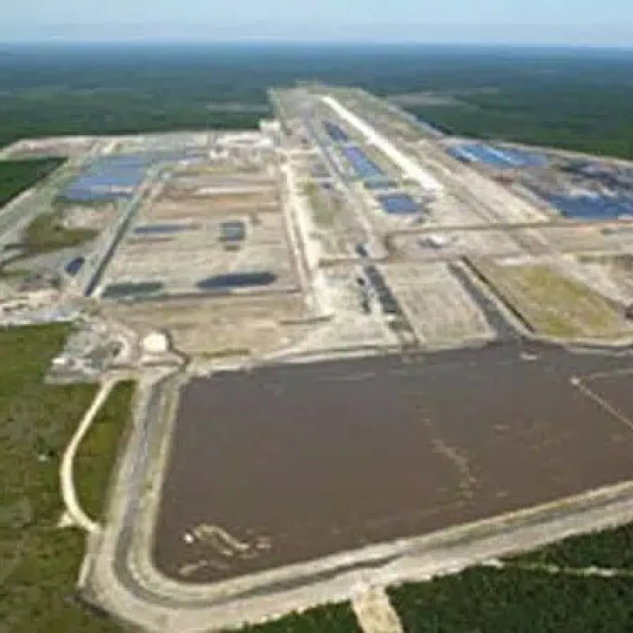 Aerial view of a large industrial wastewater treatment facility surrounded by forest and multiple containment ponds.