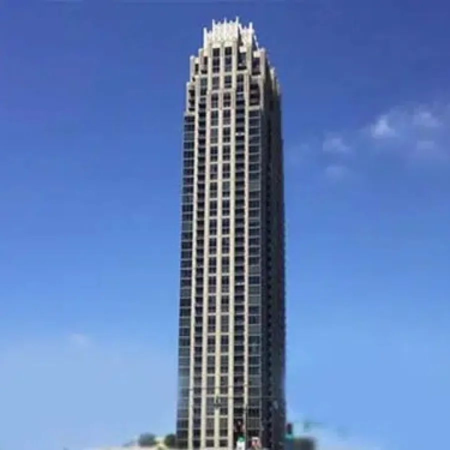 Tall modern skyscraper with grid-like windows under a clear blue sky during daytime.