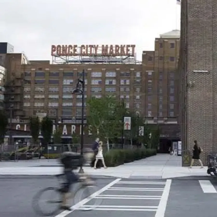 Ponce City Market building with a white shuttle bus and cyclist on a city street in Atlanta.