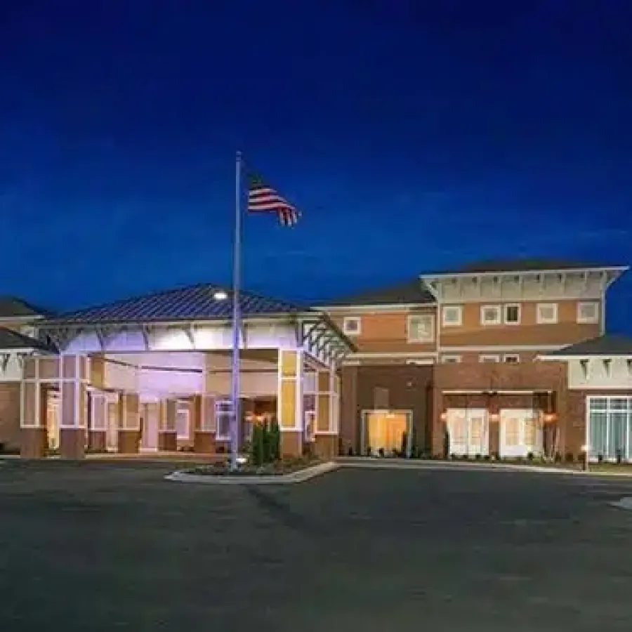 Large brick building with white columns and American flag at night under a dark blue sky.