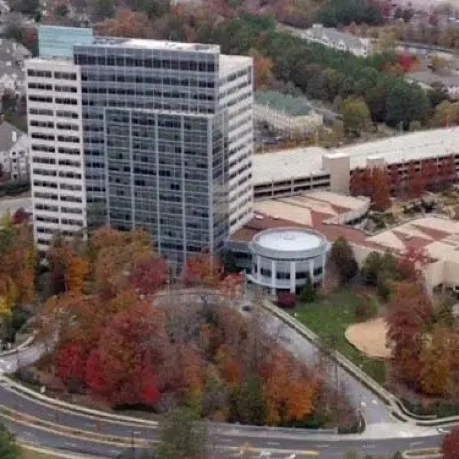 Aerial view of office buildings surrounded by autumn trees and winding roads in a suburban area.