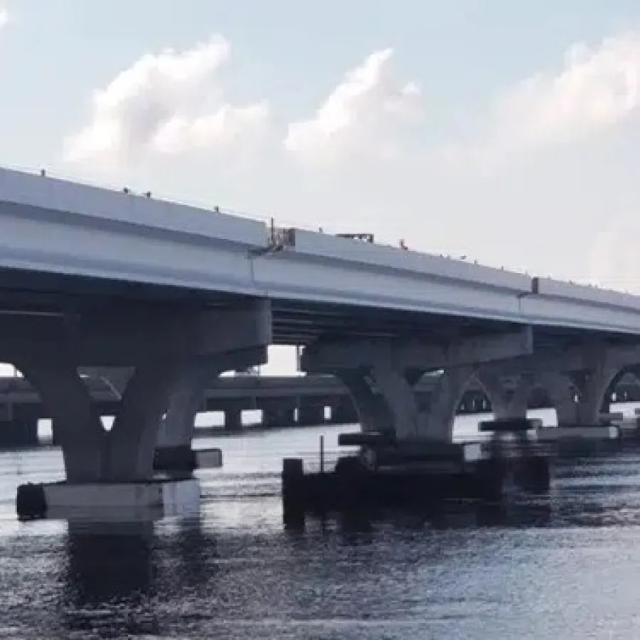 Modern concrete bridge spans calm water under a partly cloudy sky during daylight hours