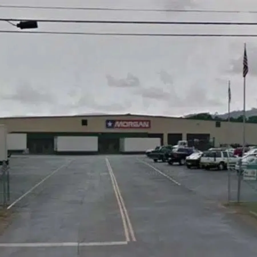 Morgan warehouse building with parking lot, trucks, and American flags on cloudy day