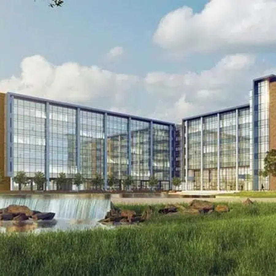 Modern glass and brick office building with landscaped greenery and a small waterfall under a partly cloudy sky.